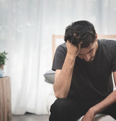 Stressed man sitting on the edge of his bed