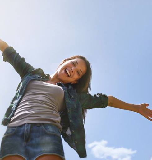 Happy woman standing outside with blue sky in background