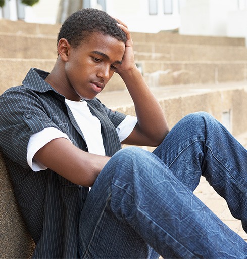 Depressed teen boy sitting outside