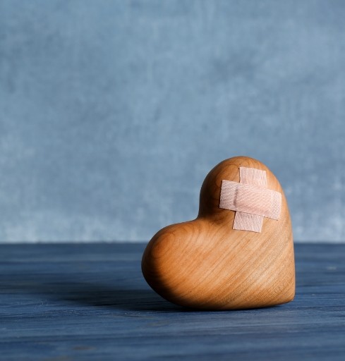 Wooden heart with a bandage on it representing grief