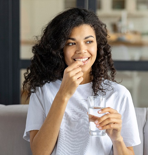 Smiling woman swallowing a supplement