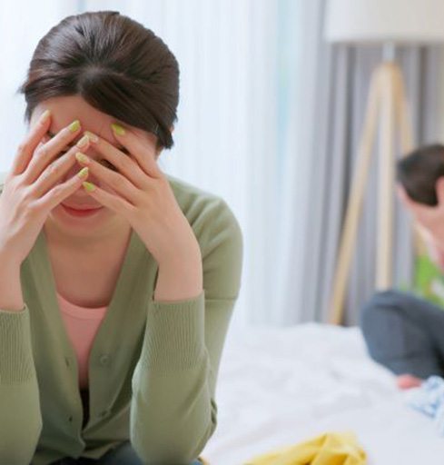 Troubled mom, with dad holding baby in background